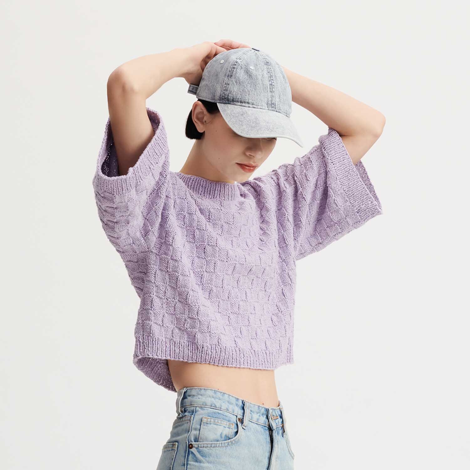Strickanleitung Shirt aus Essentials Super Cotton dk: Lila gestricktes Shirt, lässiger Schnitt, kombiniert mit hellblauer Jeans und grauer Kappe.