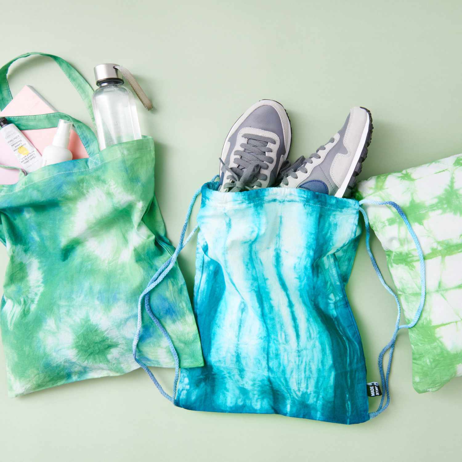 Javana Batik-Textilfarbe: Drei Stofftaschen in Grün- und Blautönen, gefärbt mit Batik-Technik.