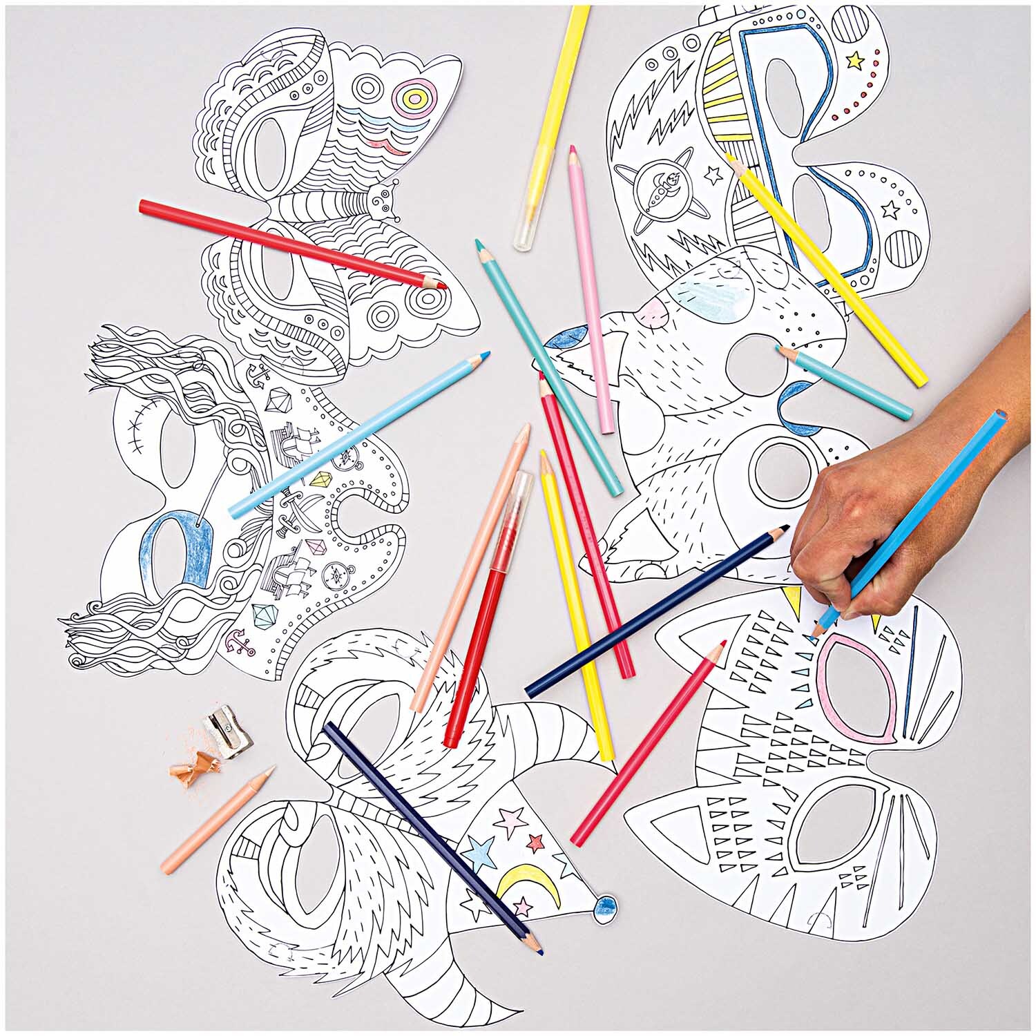Paper Poetry Buntstifte im Metalletui 12 Stück: Eine Hand malt bunte Masken mit Stiften von Rico Design.