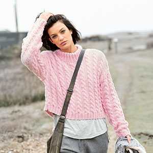 Frau trägt rosa Zopfmuster-Pullover.