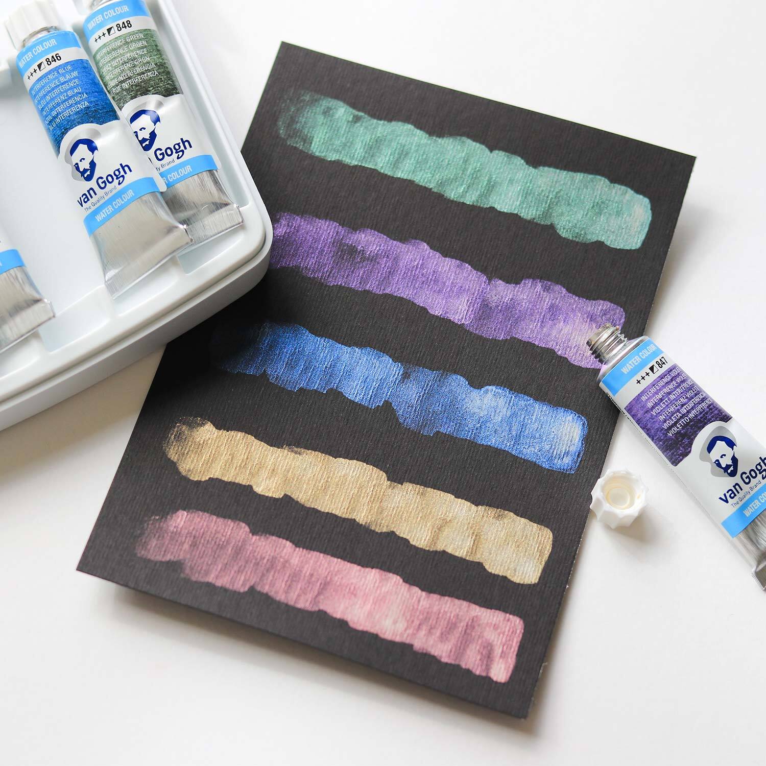 Aquarellfarben-Set Specialty Farben 12x 10ml von van Gogh zeigt lebendige Farbstreifen auf schwarzem Papier.