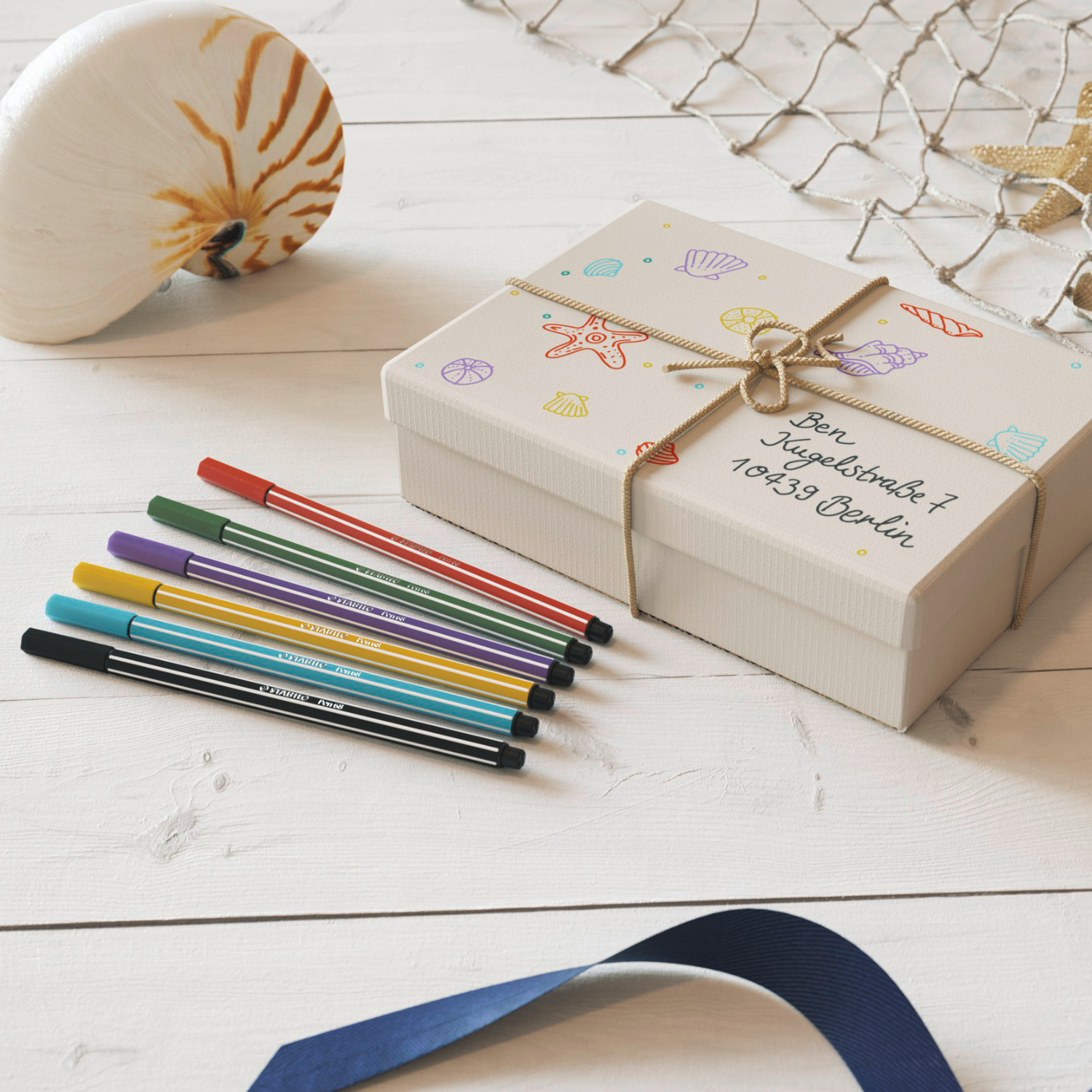 Pen 68 von STABILO in einer kreativen Szene mit Muschel und Geschenkbox auf Holzuntergrund.