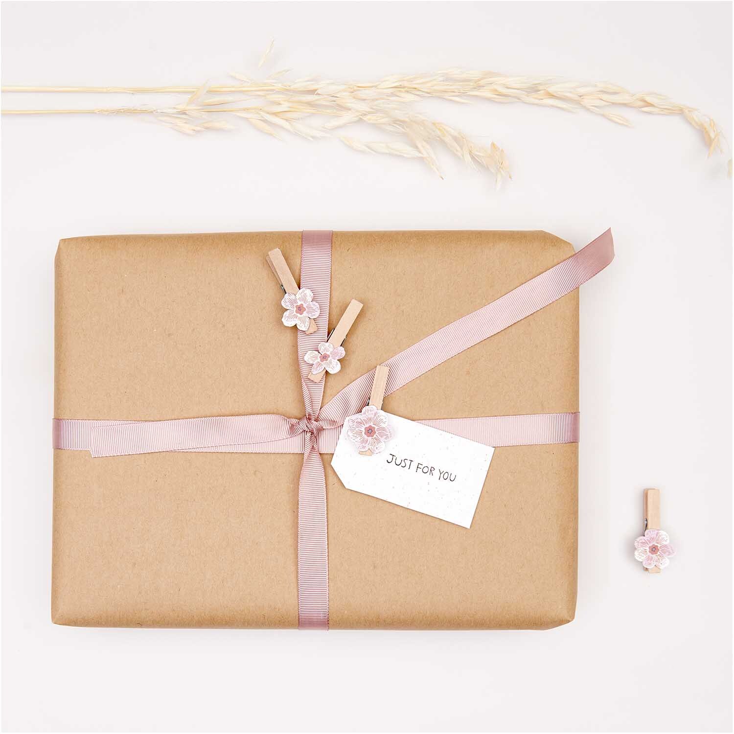 Dekoklammern Blüte mauve 4 Stück von Rico Design auf Geschenk mit rosa Band und Blütenmotiv.