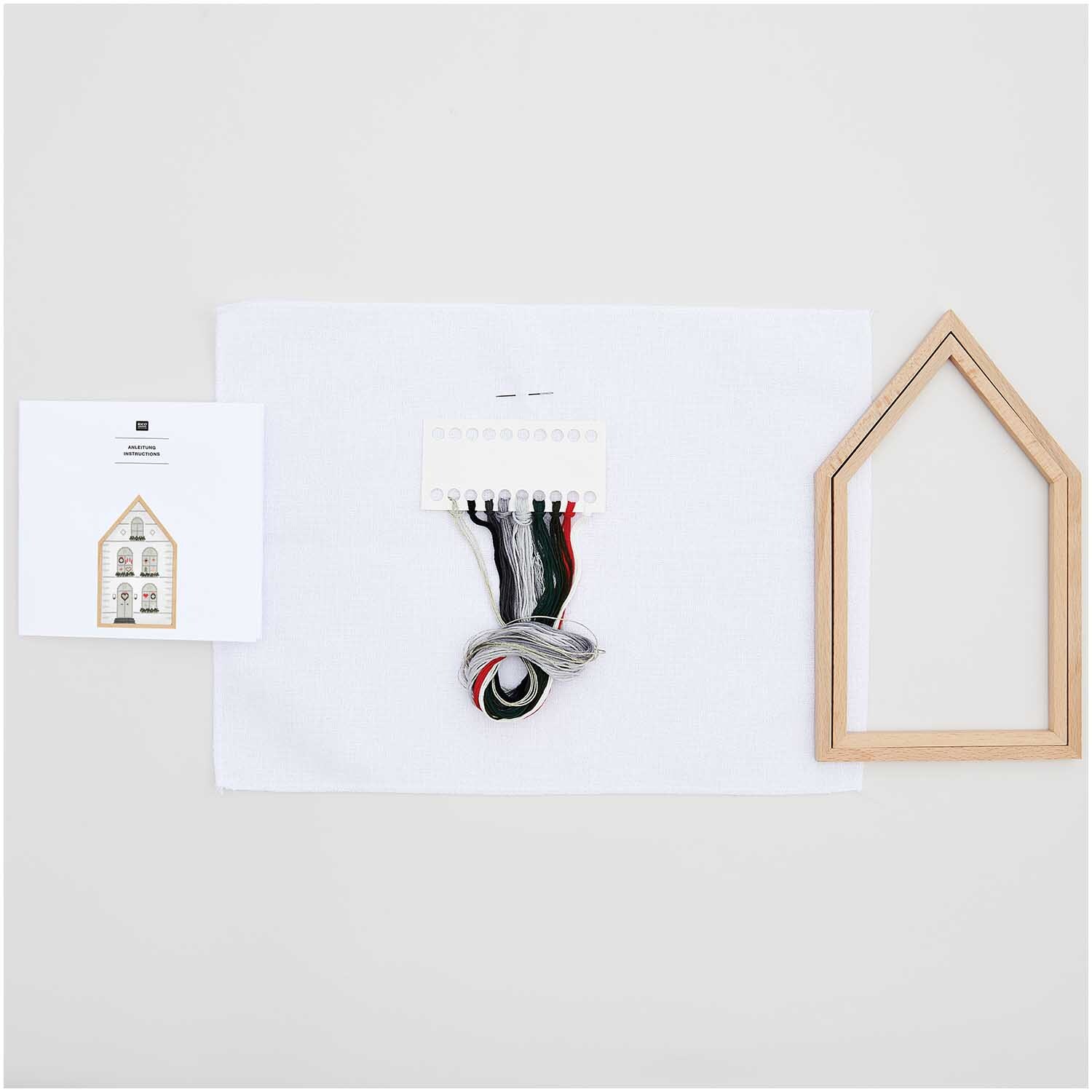 Stickpackung Haus groß 16x27cm von Rico Design: Set mit Holzrahmen, Garn und Anleitung auf weißem Hintergrund. Ideal für kreative Projekte.