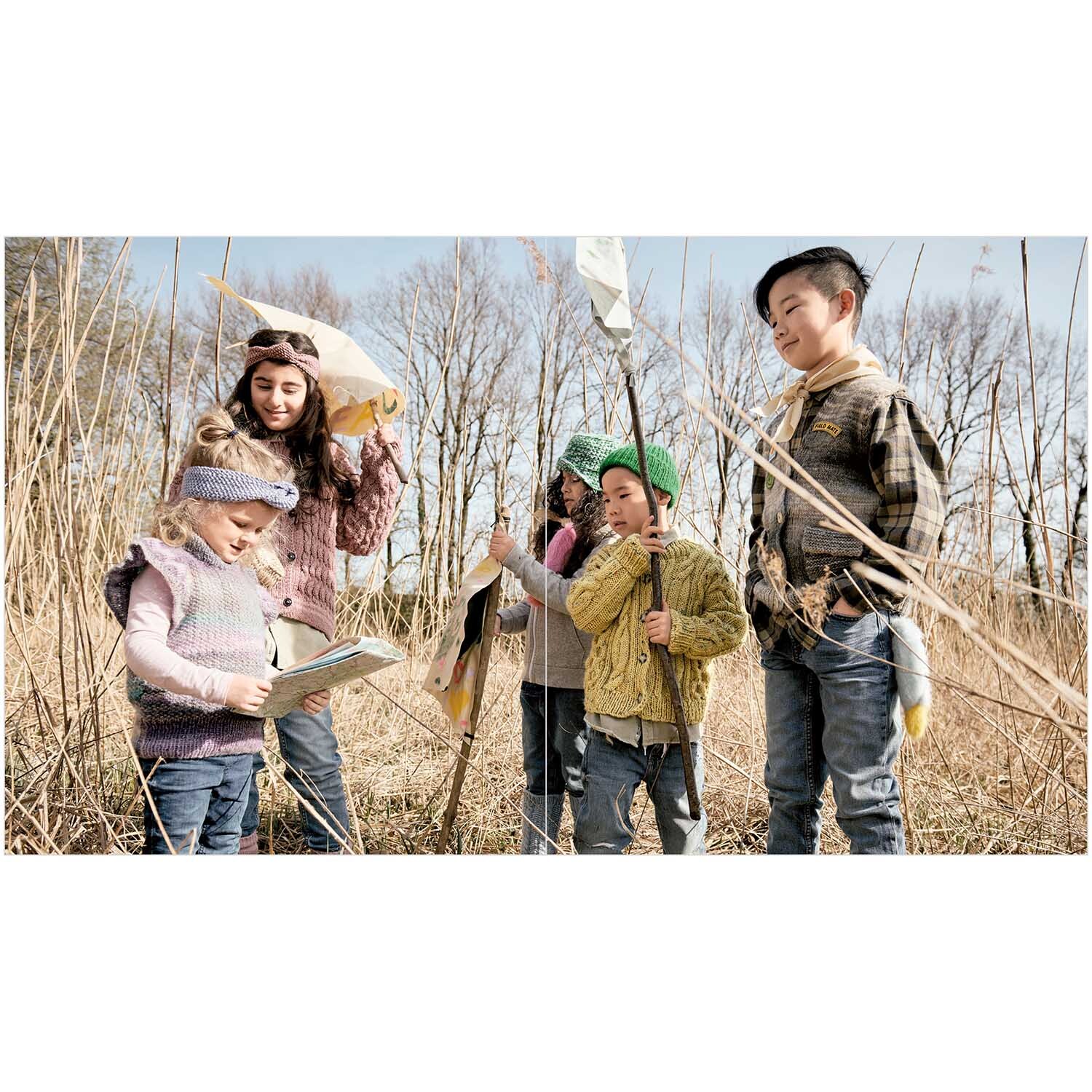 Kids Nr.11: Kinder in bunter Strickmode von Rico Design erkunden eine Wiese mit Schmetterlingsnetzen.