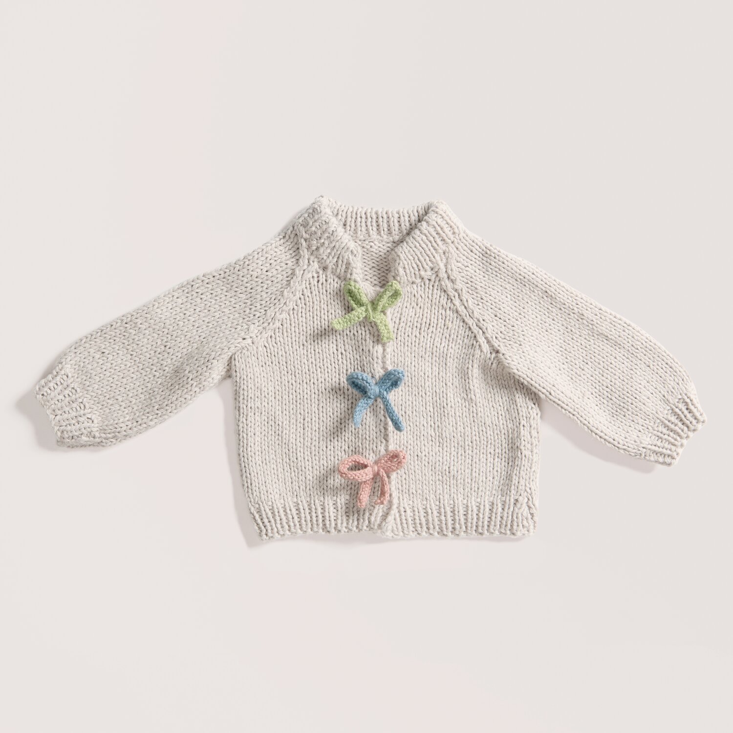 Rico Baby 043 Pullover aus Bio-Baumwolle und Kaschmir mit bunten Schleifen in sanften Pastelltönen.