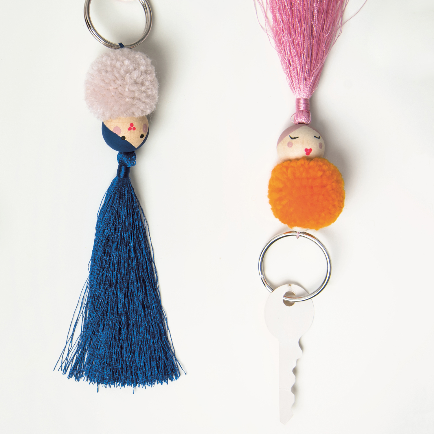 Bastelanleitung Schlüsselanhänger aus Pompons und Quasten zeigt zwei bunte Anhänger mit Pompons und Quasten in Blau und Pink.