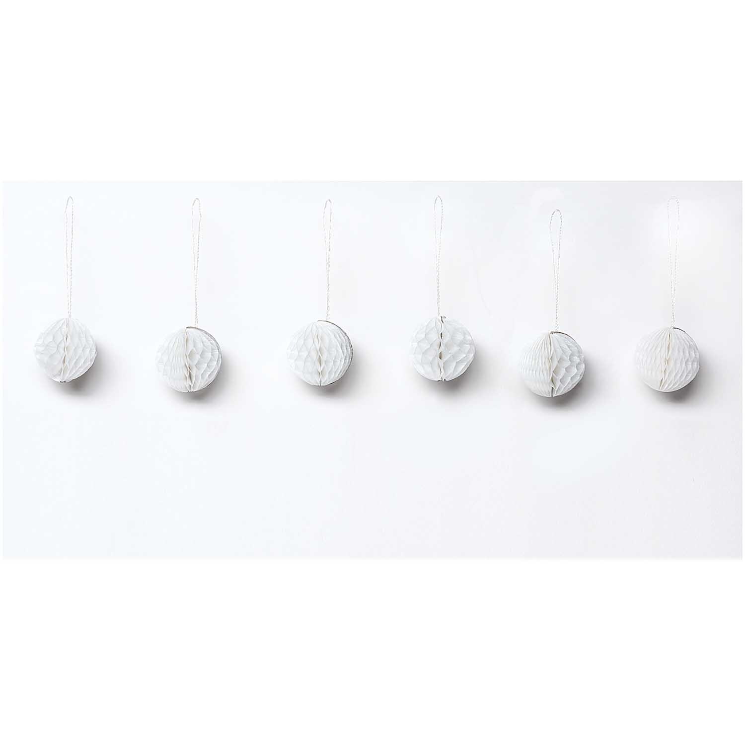 Mini-Wabenbälle 4cm 6 Stück von Rico Design in Weiß, dekorativ an einer Wand aufgehängt.