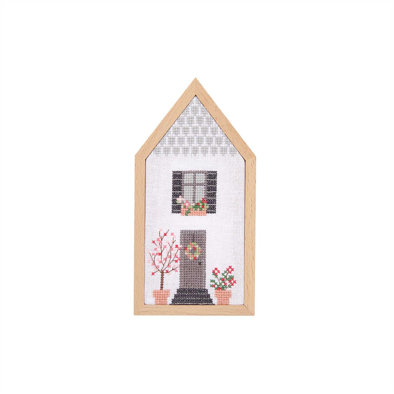 Dekorahmen Haus Hochformat zeigt ein gesticktes Haus mit Blumen in einem Holzrahmen von Rico Design.