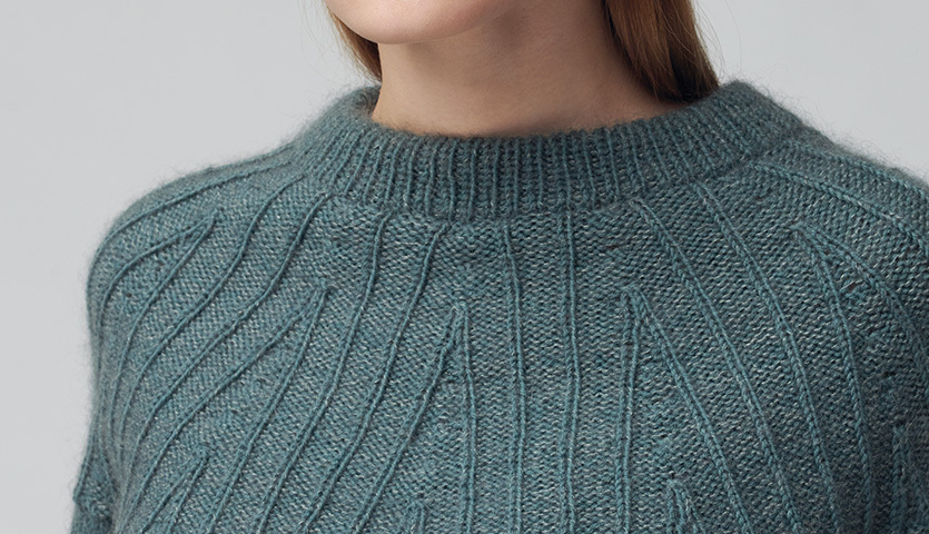 Strickanleitung Top Down Knitting Pullover: Nahaufnahme eines gestrickten Pullovers in Blaugrün mit Rippenmuster.