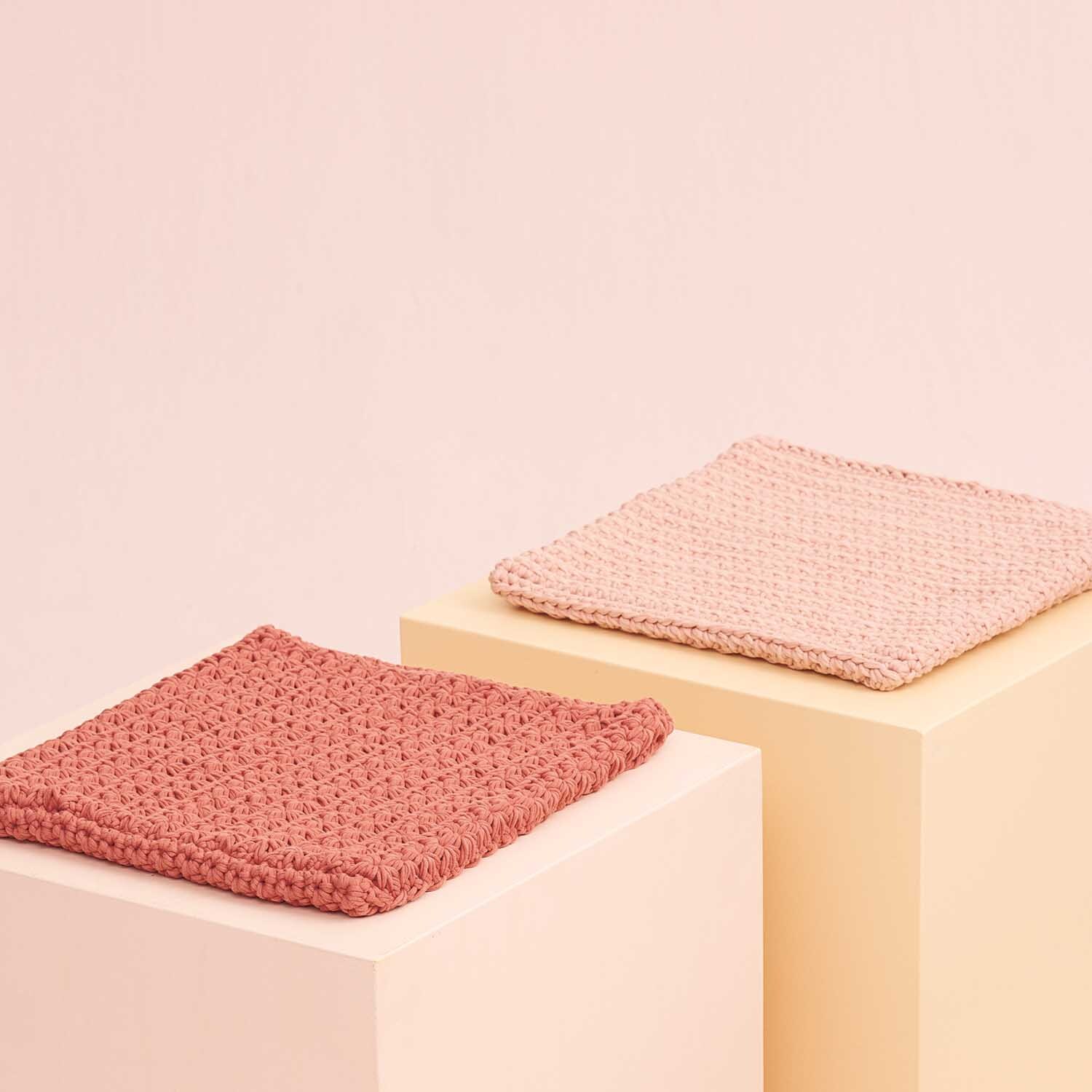 Fashion Jersey: Zwei gestrickte Stoffproben in Rosa und Terracotta auf hellen Podesten präsentiert.