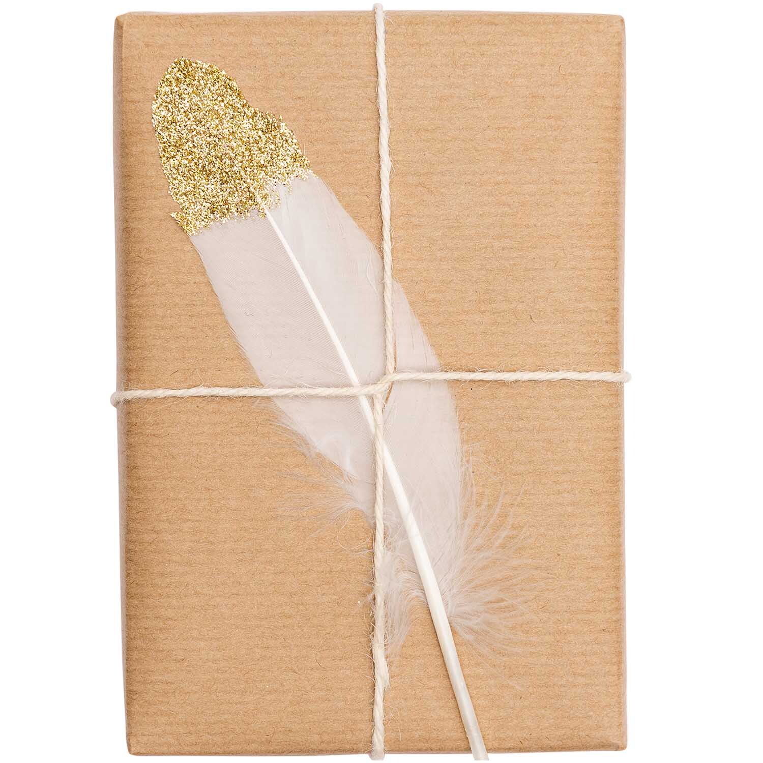 Federn ca. 8cm 6 Stück: Eine weiß-goldene Feder liegt auf einem braunen, mit Schnur gebundenen Paket.
