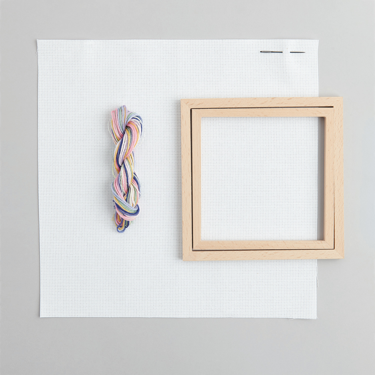 Stickpackung Bild Herzkranz im Dekorahmen von Rico Design zeigt Garn und Holzrahmen auf weißem Stoff.