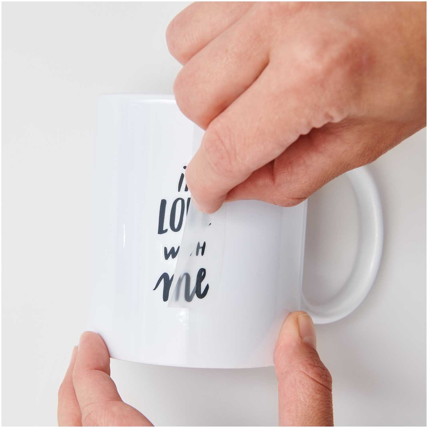Transfermotiv Good Things are Coming: Hände kleben ein Motiv auf eine weiße Tasse. Marke: Rico Design.