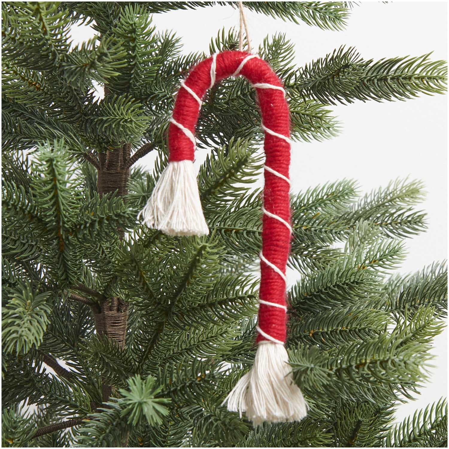 Makramee Set Zuckerstange, dekorativer Baumschmuck in Rot und Weiß, hängt an einem Tannenzweig.