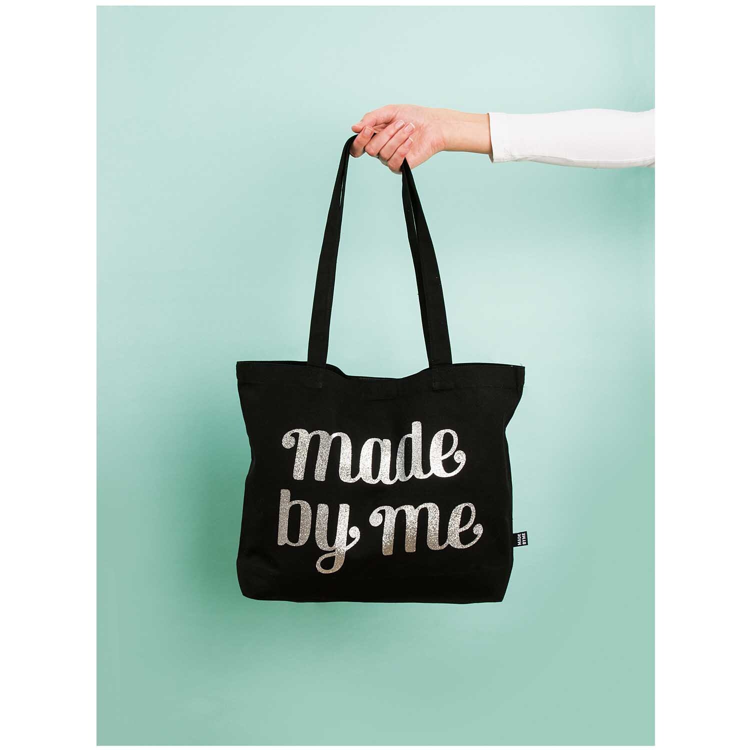 Tasche mit langen Henkeln, 44,5x34x33,5cm, von Rico Design. Schwarze Tasche mit Schriftzug "made by me", gehalten von einer Hand.