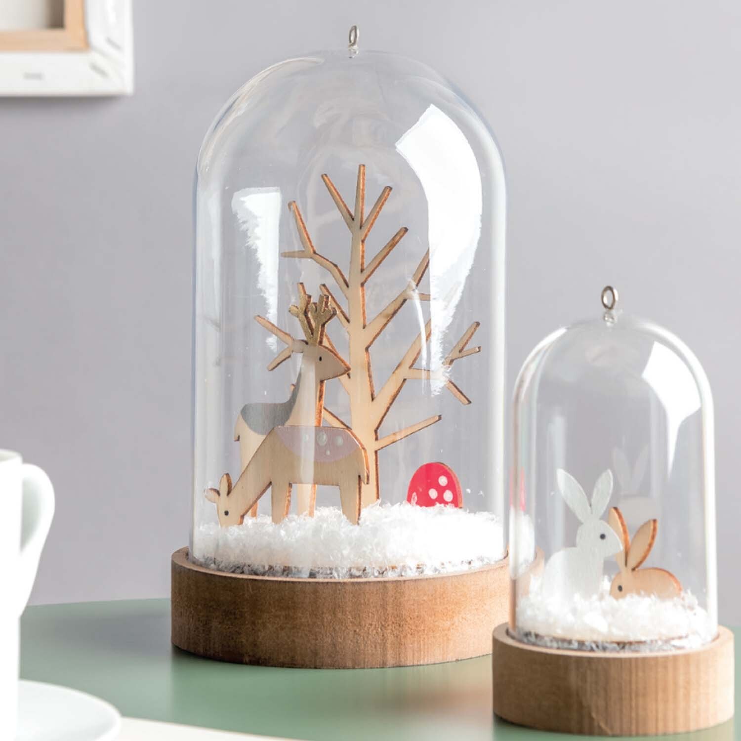 Bastelanleitung Dekohauben: Zwei Glasglocken mit Holzsockel, gefüllt mit Schneelandschaft, Hirsch und Hase. Ideal für winterliche Dekorationen.