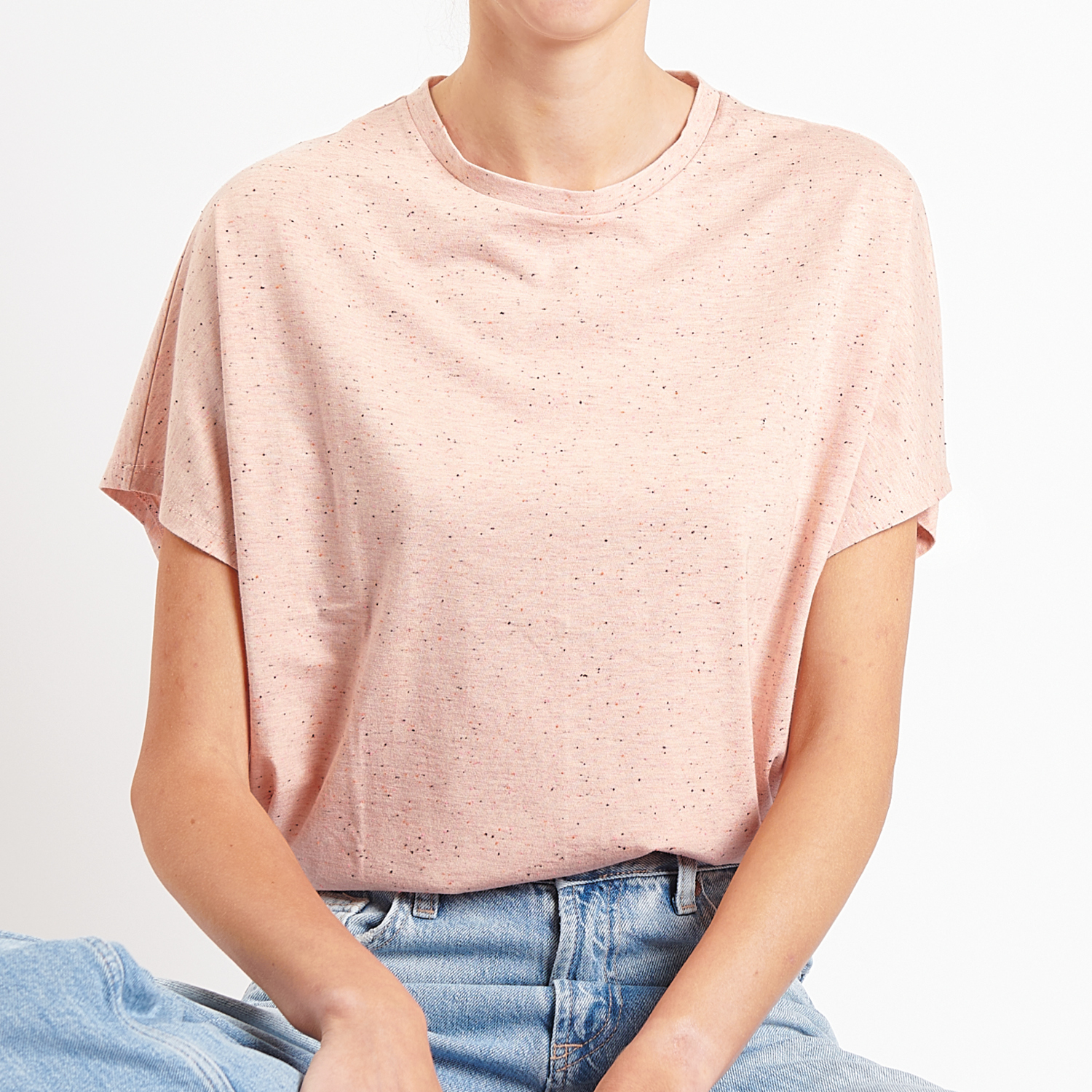 Nähanleitung lockeres Kurzarm-Shirt: Frau trägt ein lässiges, rosa T-Shirt, kombiniert mit blauen Jeans.