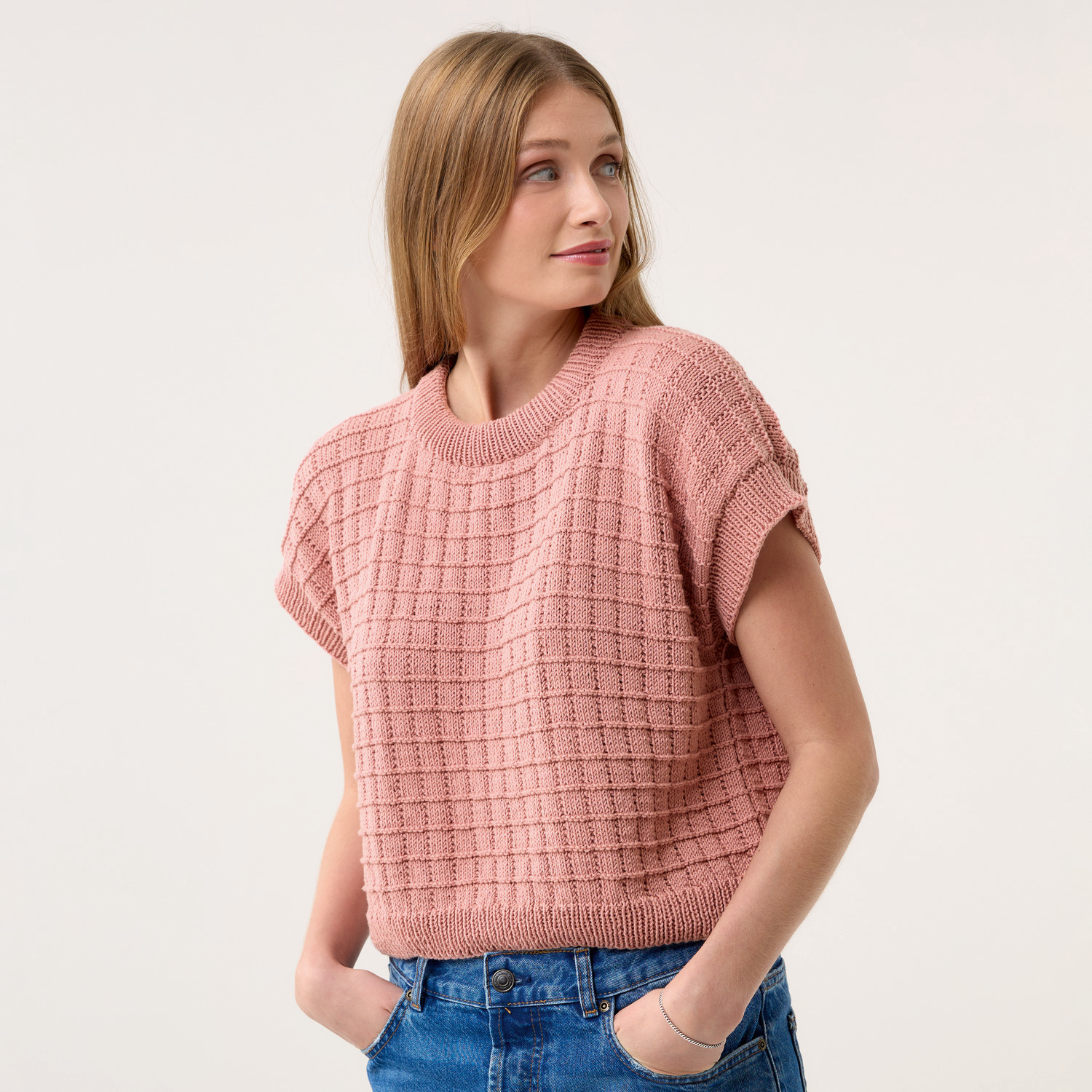 Strickset Shirt Modell 15: Frau trägt ein rosa gestricktes Shirt mit kurzen Ärmeln und Rundhalsausschnitt.