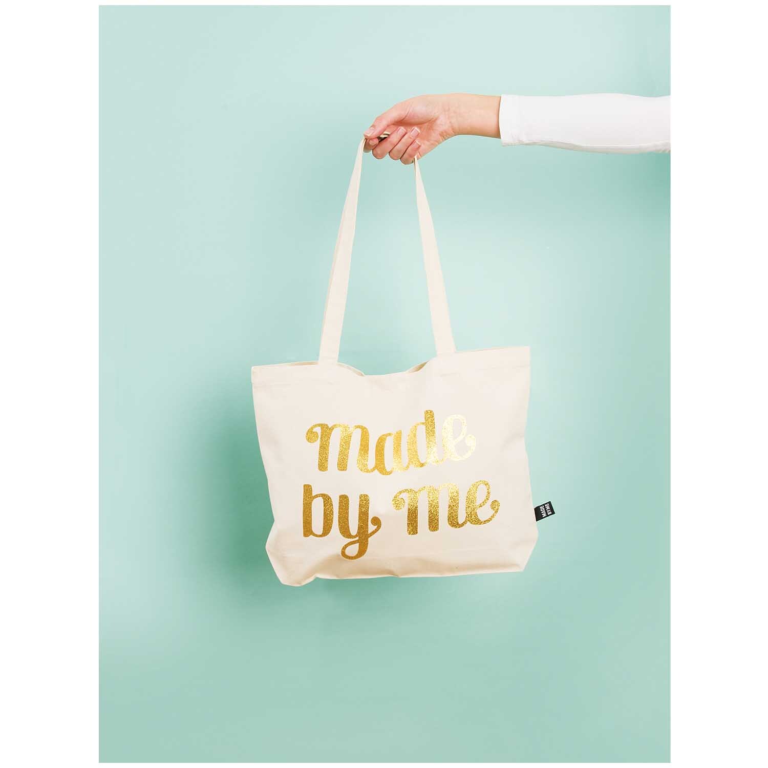 Tasche mit langen Henkeln von Rico Design, gehalten von einer Hand, mit goldener Aufschrift "Made by Me".