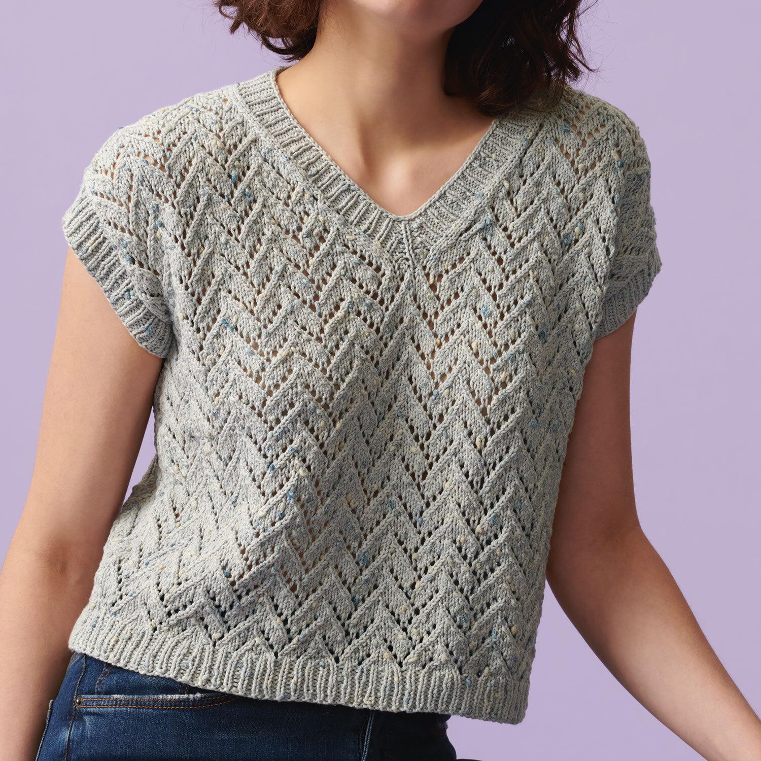 Strickanleitung Top mit Zickzack-Muster aus Baumwolle, getragen von Frau vor lila Hintergrund.