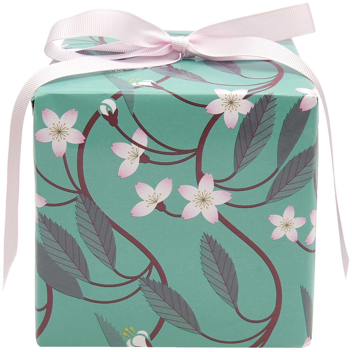 Paper Poetry Geschenkpapier mit Kirschblütenranken auf mintfarbenem Hintergrund, verpackt mit rosa Schleife. Ideal für stilvolle Geschenke.