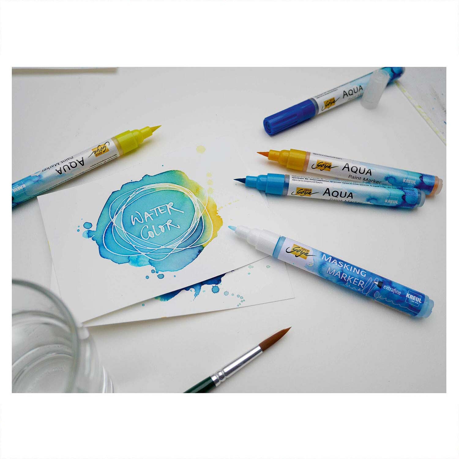 Solo Goya Masking Marker in verschiedenen Farben auf einem Tisch mit Aquarellzeichnung und Pinsel.