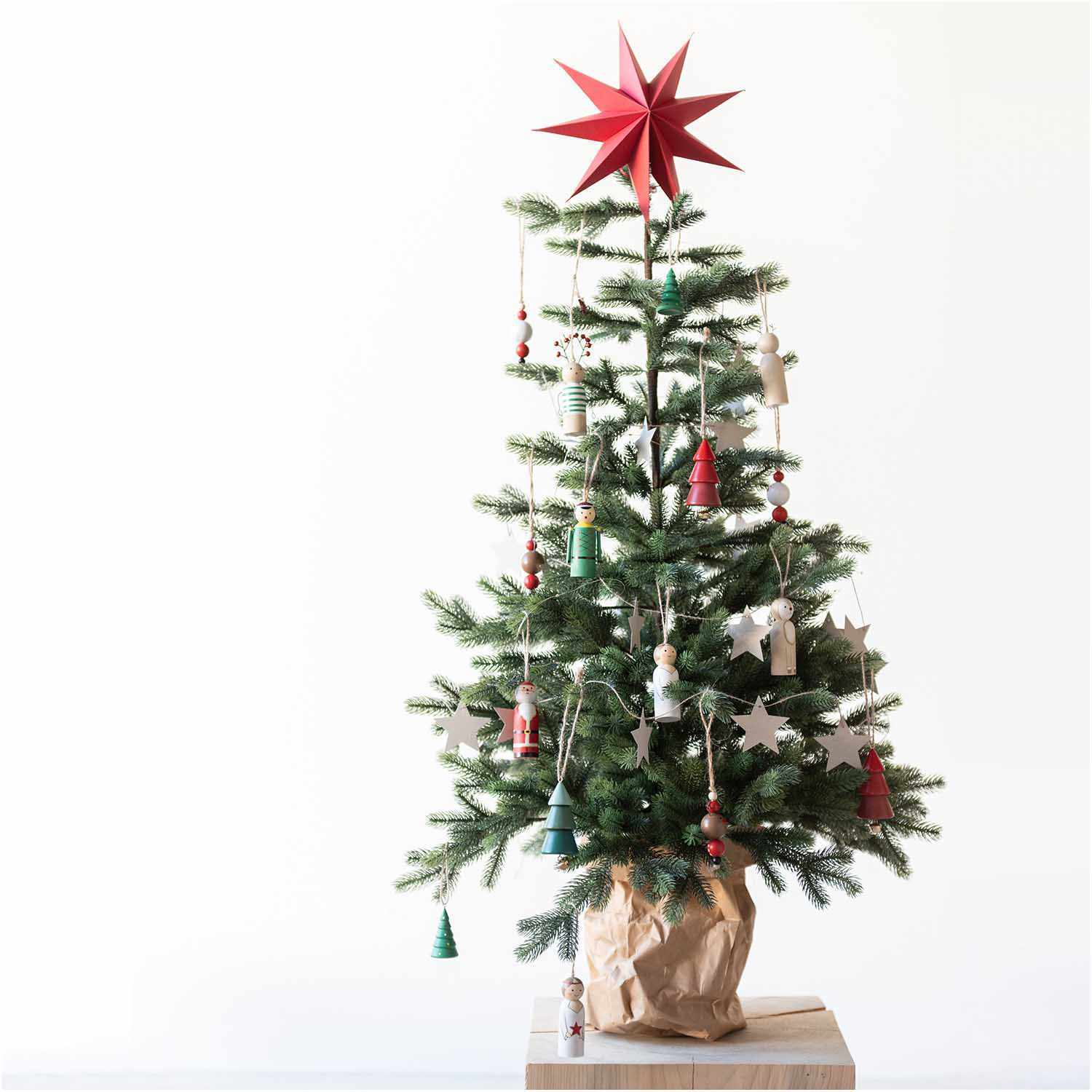 Holzhänger Nussknacker rot 3x9cm von Rico Design schmückt einen Weihnachtsbaum mit roten und weißen Ornamenten und einem roten Stern an der Spitze.