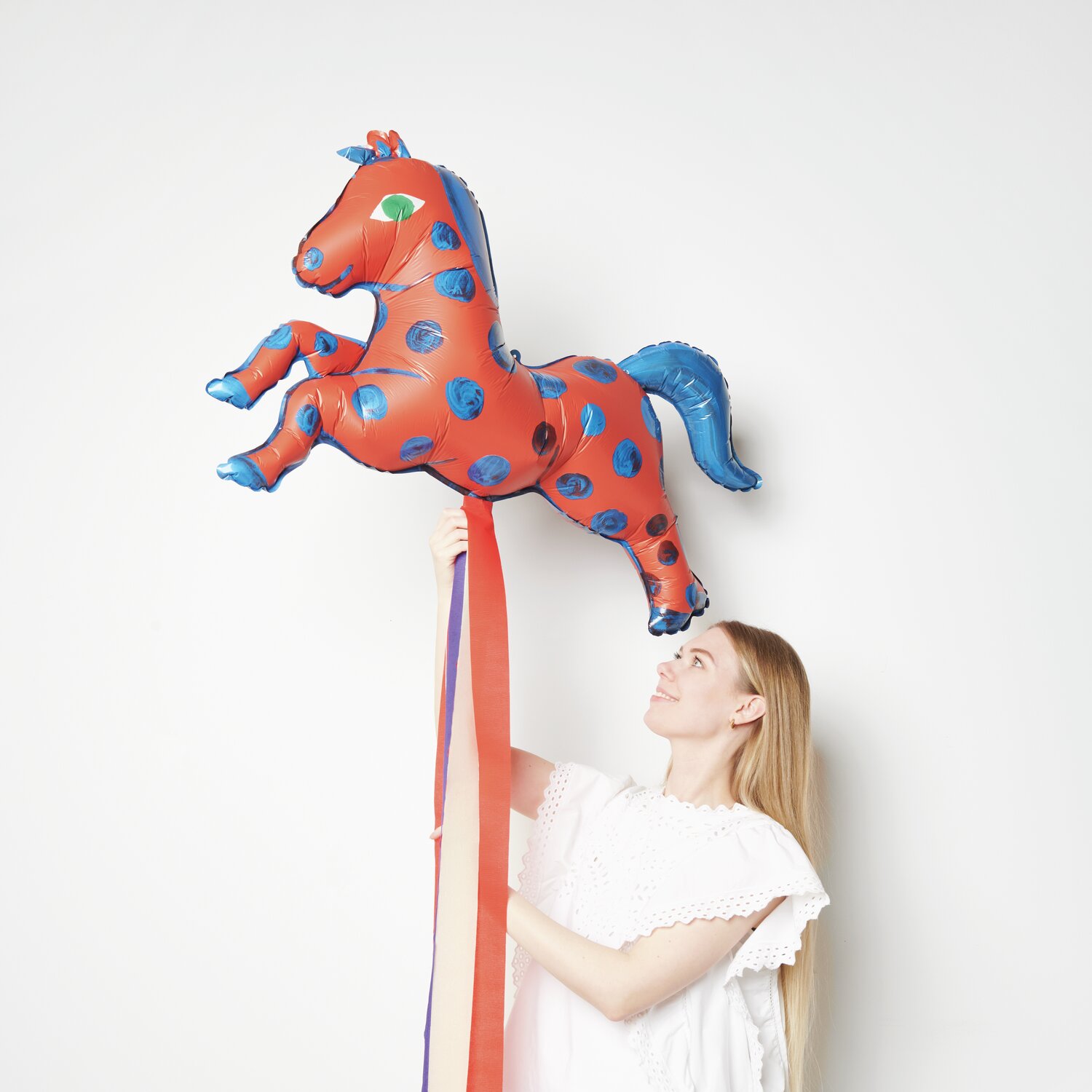 Folienballon Pferd Rot/Blau von Rico Design, gehalten von einer Person, zeigt ein buntes Pferd in der Luft.