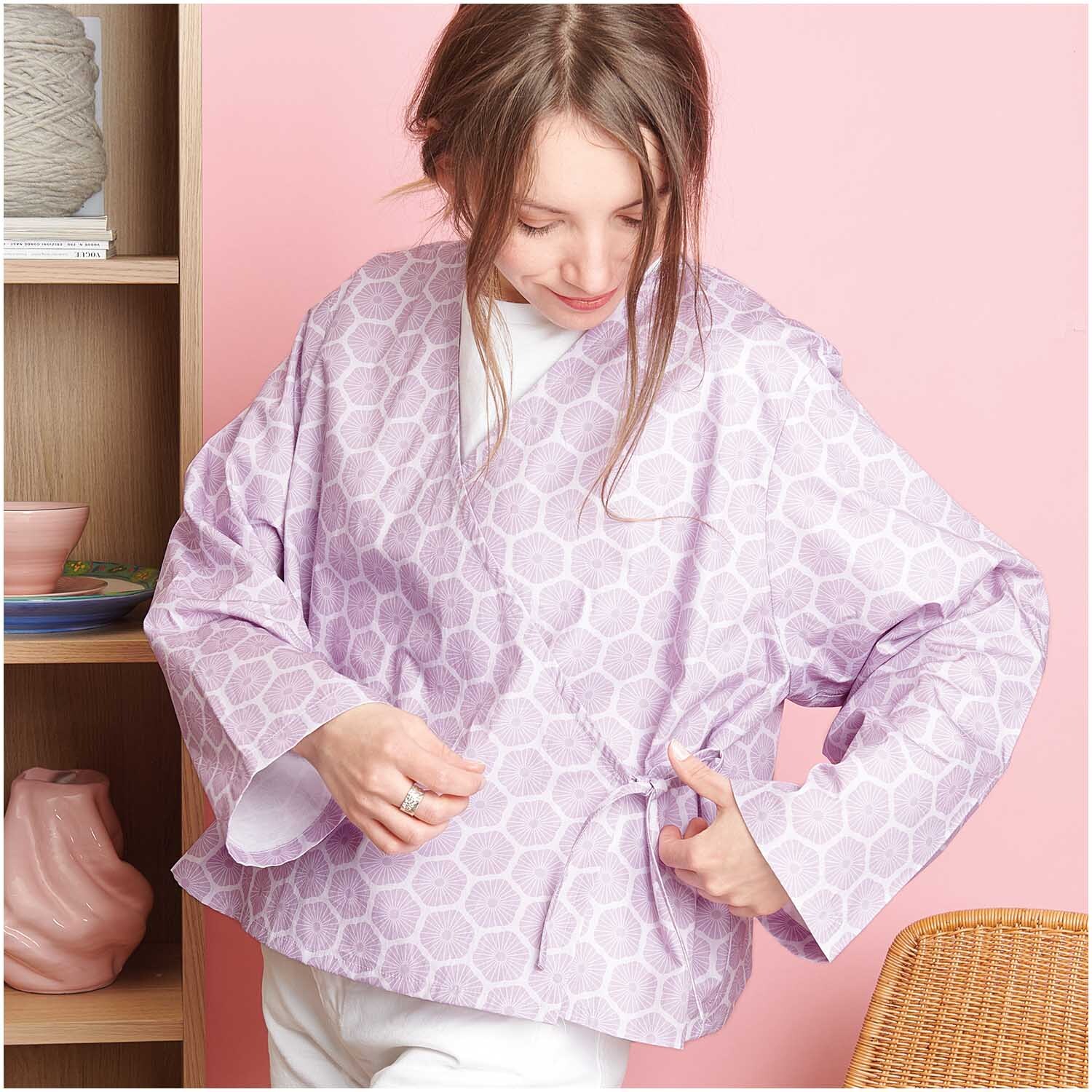 Meterware Baumwoll-Popelin flieder Rosette von Rico Design: Frau trägt fliederfarbenen Kimono vor rosa Hintergrund.