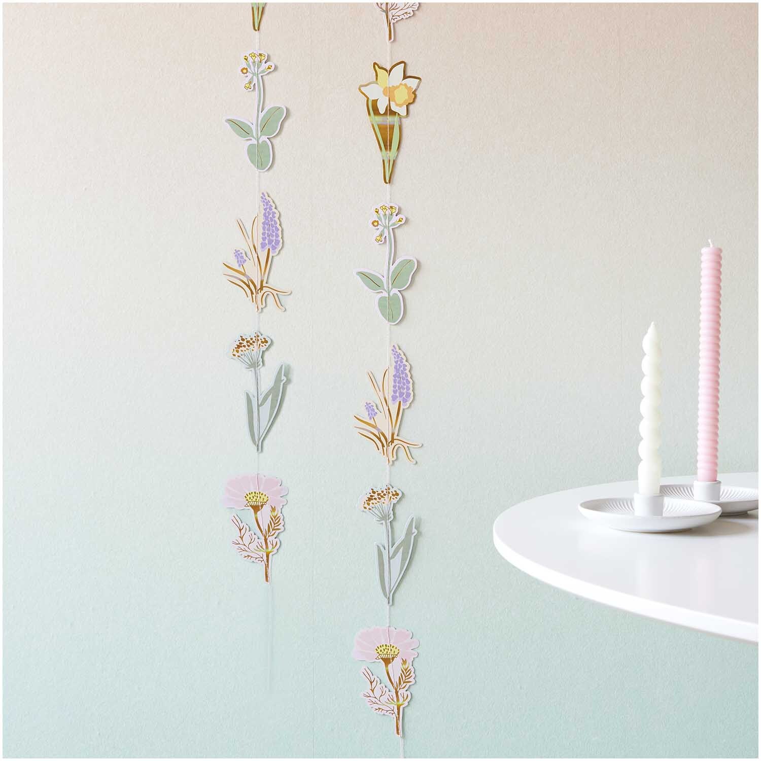 Paper Poetry genähte Girlande Osterwiese mit floralen Motiven, dekorativ hängend an einer Wand. Perfekt für Frühlingsdekorationen.