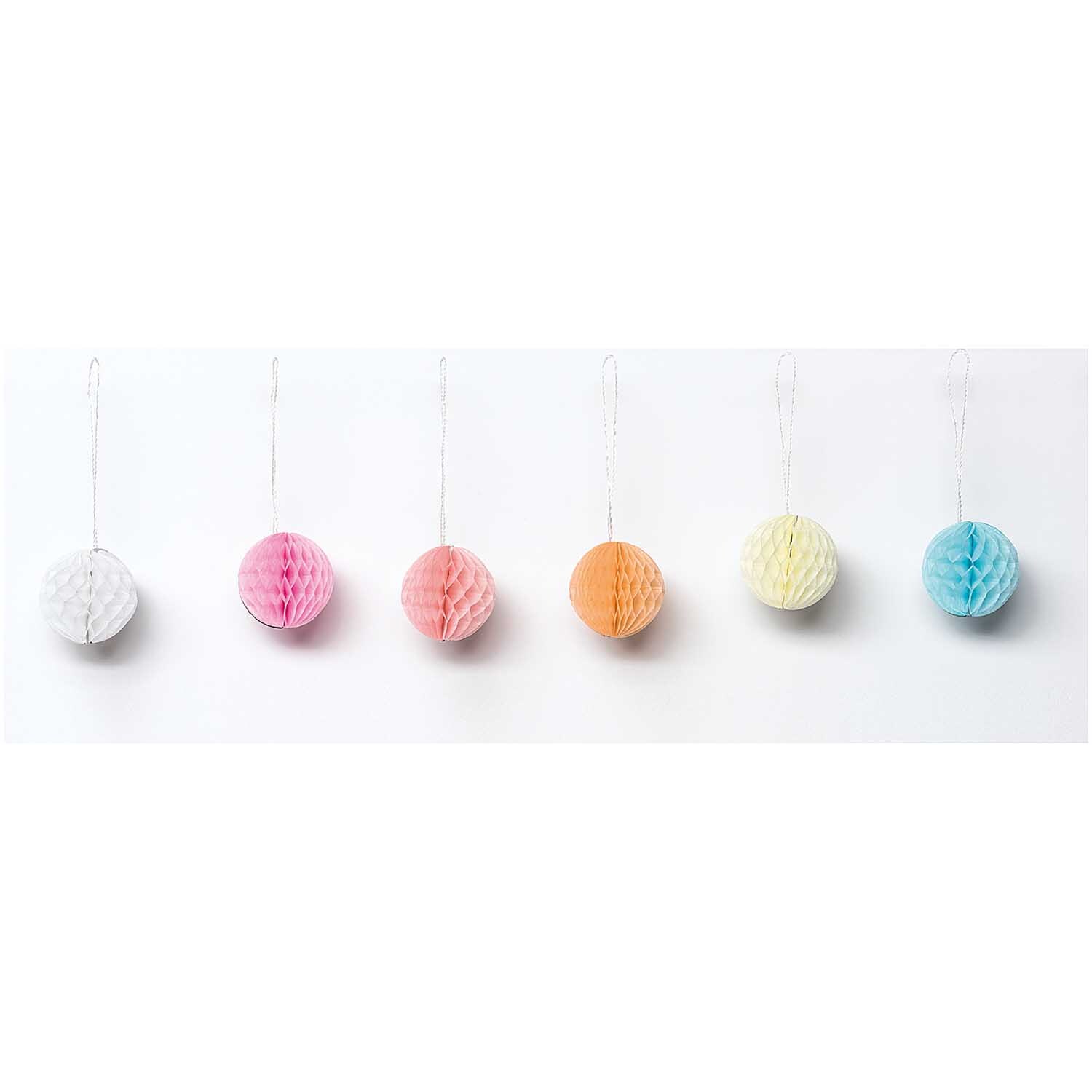 Mini-Wabenbälle 4cm 6 Stück in Pastellfarben von Rico Design, aufgehängt in einer Reihe.