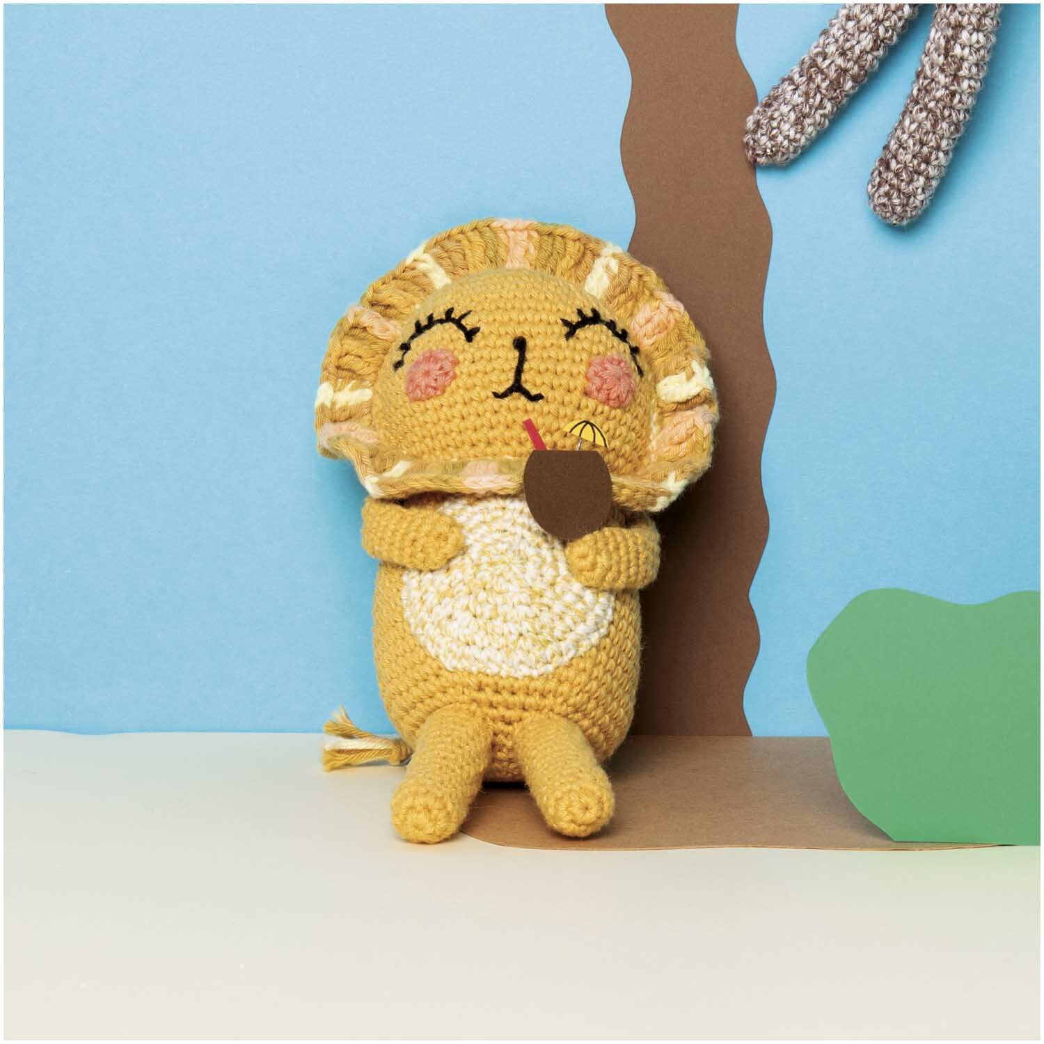 Creative Ricorumi dk Set Limited: Gehäkelter Löwe mit Eis am Stiel, vor blauem Hintergrund sitzend.
