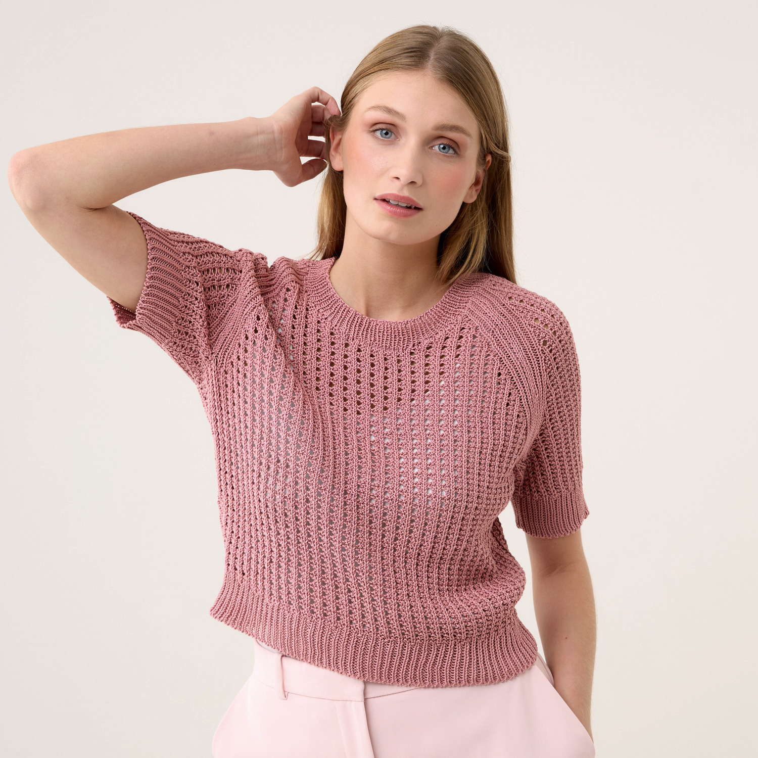 Die Neue Masche Nr. 09 Frühjahr-Sommer: Frau trägt rosa Strickoberteil von Wolle Rödel, kombiniert mit heller Hose.