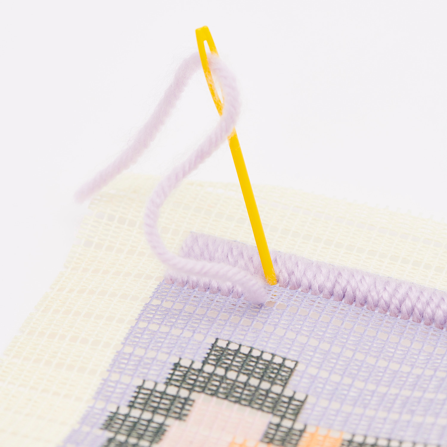 Longstitch Stickpackung Tiger: Nahaufnahme eines Stickprojekts mit gelber Nadel und lila Garn.