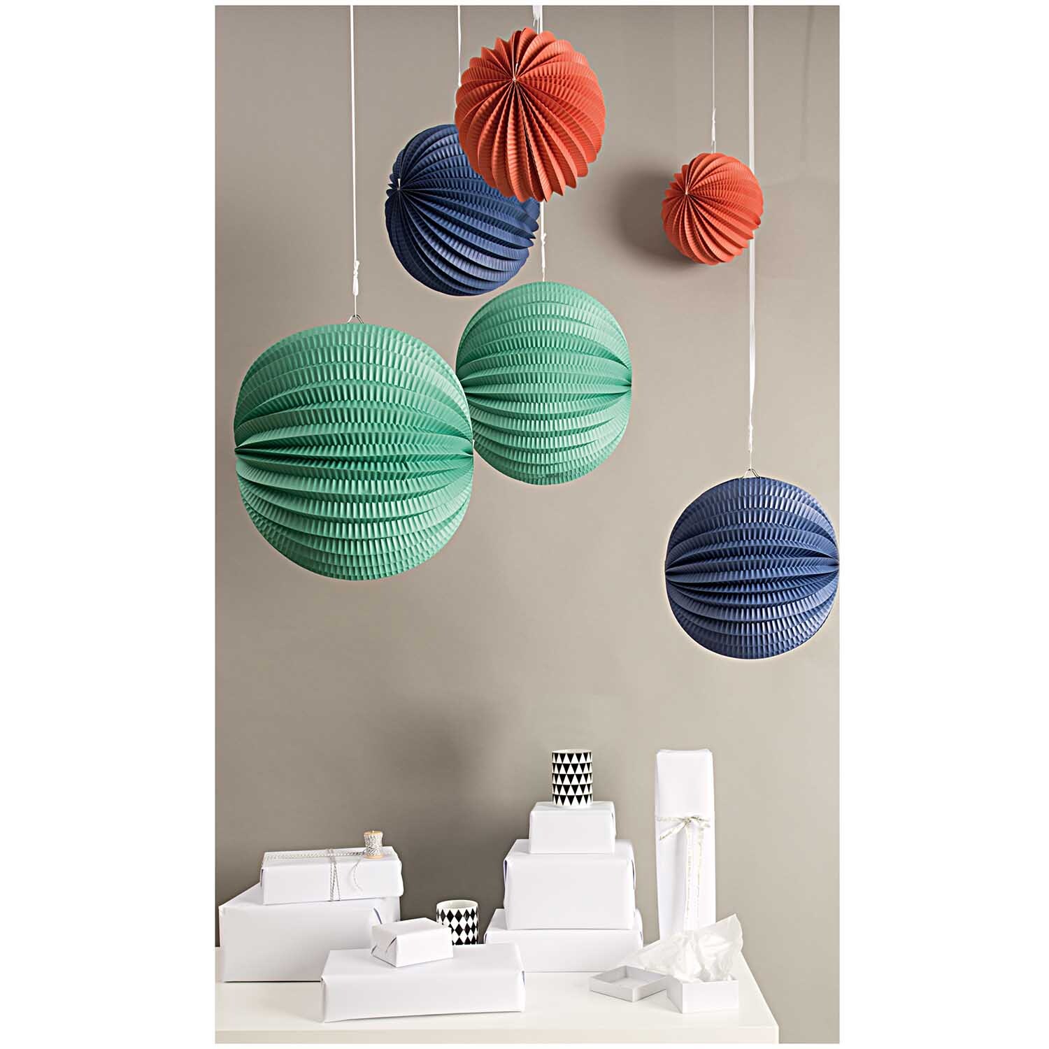 Lampions mehrfarbig 3 Stück von Rico Design, hängend in verschiedenen Farben vor grauer Wand.
