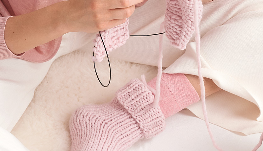 Strickanleitung Socken aus Essentials Super super chunky: Frau strickt rosa Socken mit dicker Wolle.
