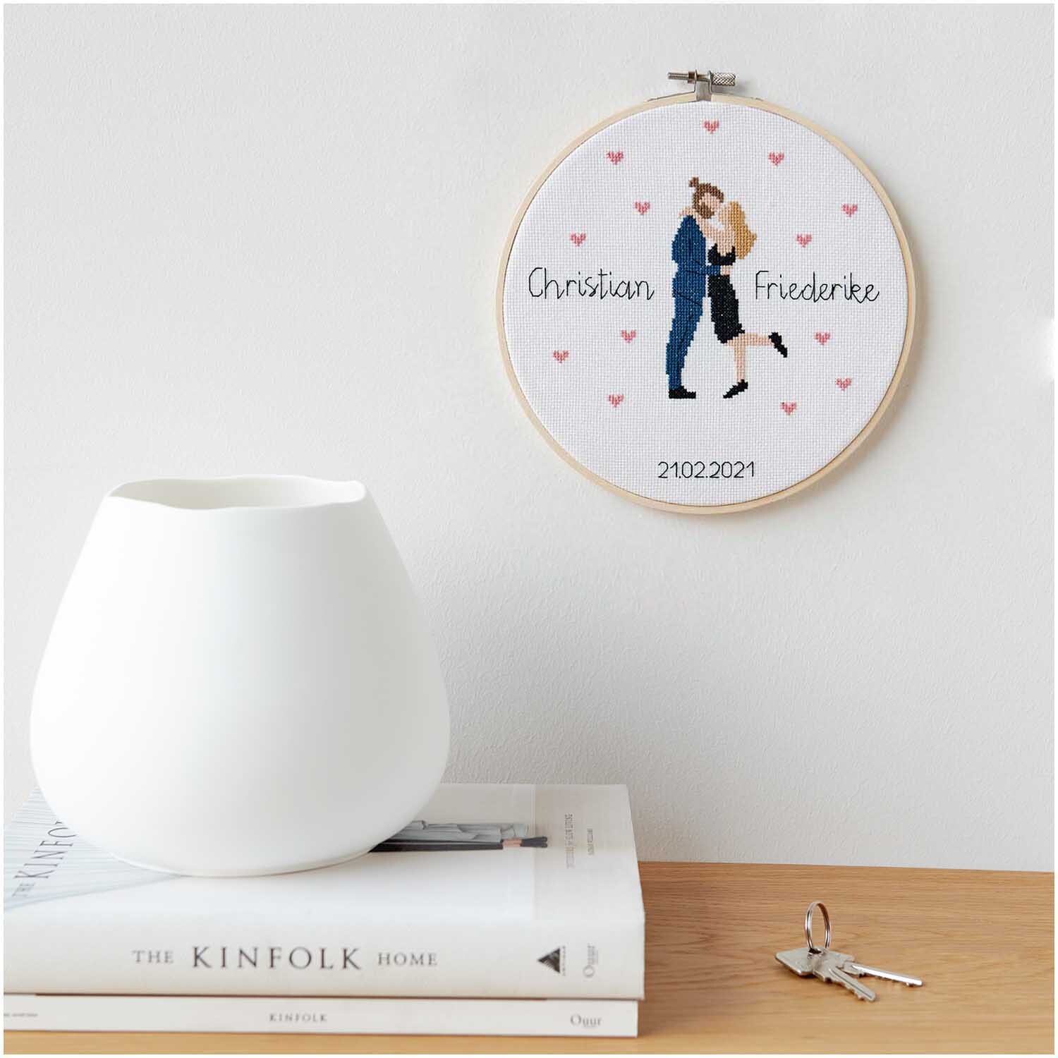 Figurico Stickpackung Lovebirds 20cm zeigt ein Paar in Umarmung, umgeben von Herzen.