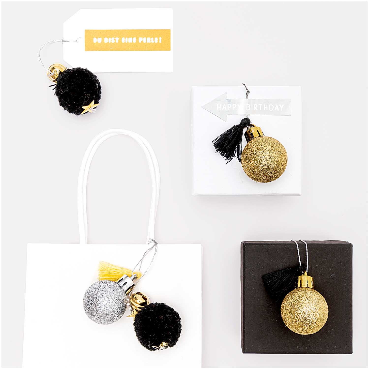 Pompon- und Kugel-Anhänger gold-silber 6 Stück von Rico Design, dekorativ auf Geschenkboxen arrangiert. Ideal für festliche Anlässe.