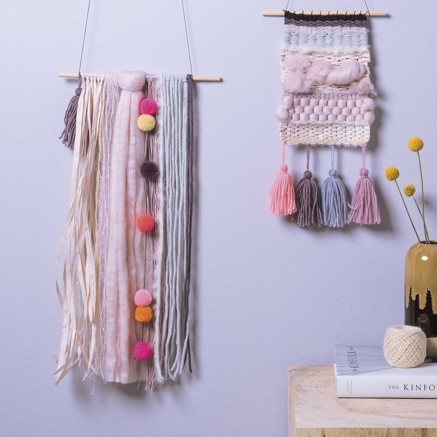 DIY Set Weben: Zwei handgefertigte Wandbehänge mit bunten Pompons und Quasten, präsentiert von Rico Design.