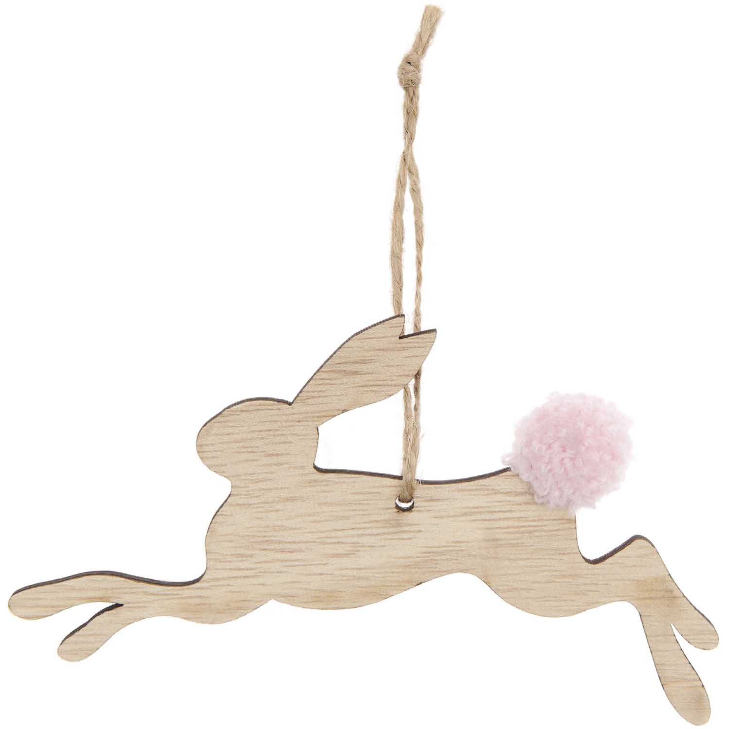 Holzanhänger Hase springend Natur: Ein naturfarbener Holzanhänger von Rico Design in Form eines springenden Hasen mit rosa Bommel.