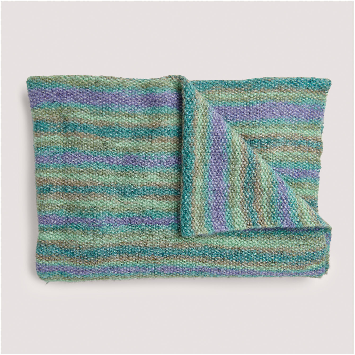 Strickset Decke Modell 15 aus Die Neue Masche Nr. 8: Bunte, gestreifte Decke in Grün- und Lilatönen, ideal für gemütliche Abende.