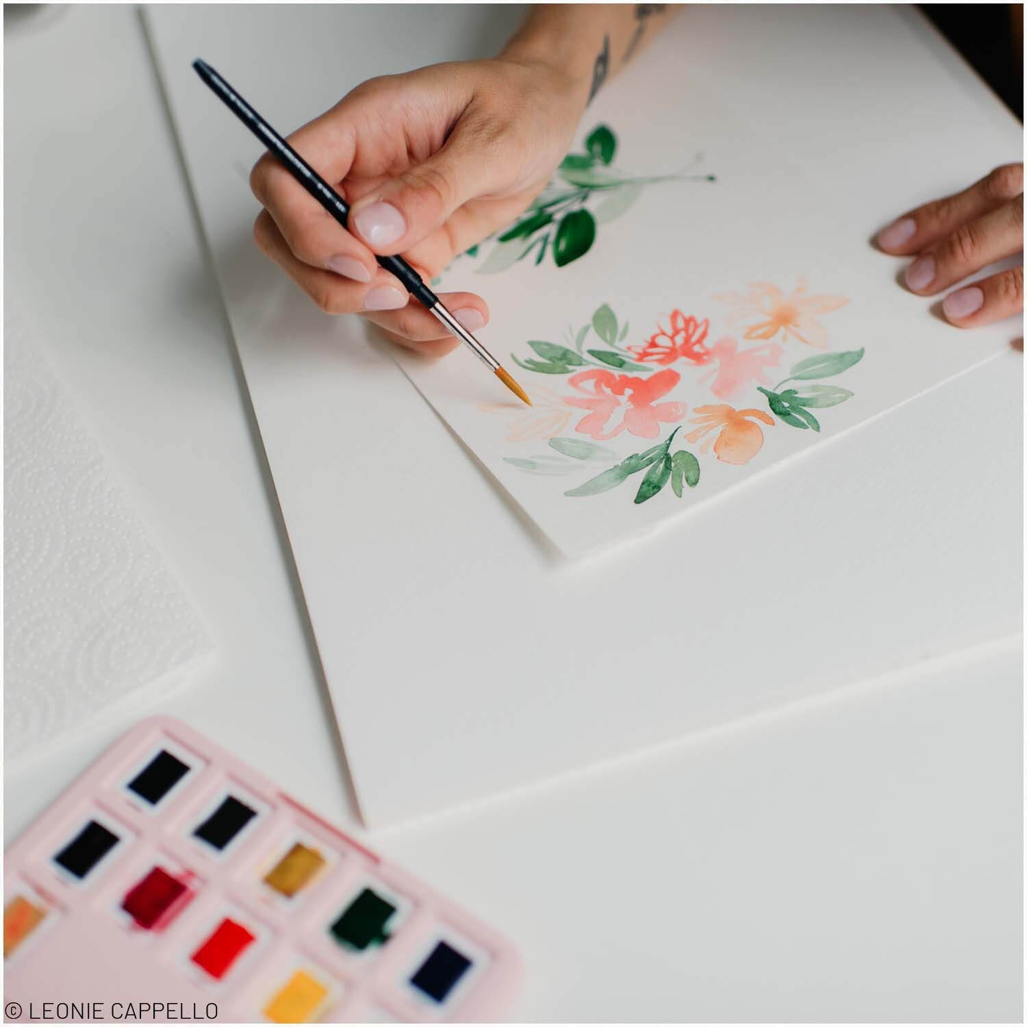 van Gogh Aquarell Set 12 Näpfchen: Eine Hand malt mit einem Pinsel bunte Blumen auf Papier.