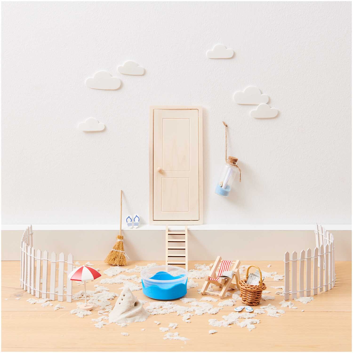 Miniatur Wichteltür natur 7,2x17,6cm vor einer weißen Wand mit Wolken, umgeben von Miniaturmöbeln und Dekorationen.