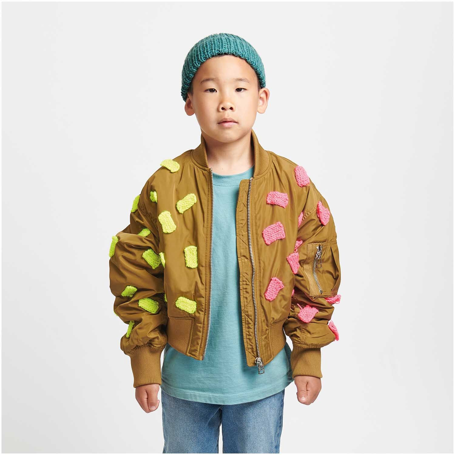 Socks Neon 4-fädig: Kind mit brauner Jacke, verziert mit bunten Stoffstücken, trägt eine blaue Mütze.