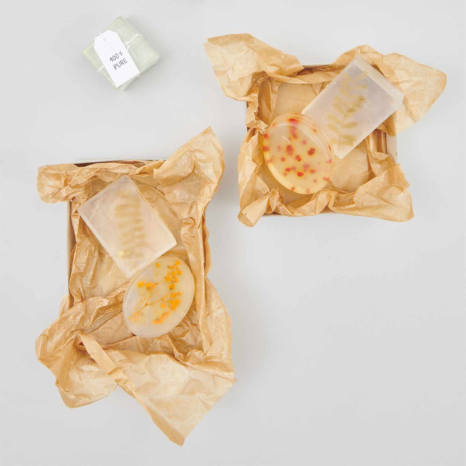 Anleitung Seife mit Blumen: Zwei handgemachte Seifen mit Blumenmuster in braunem Papier verpackt.