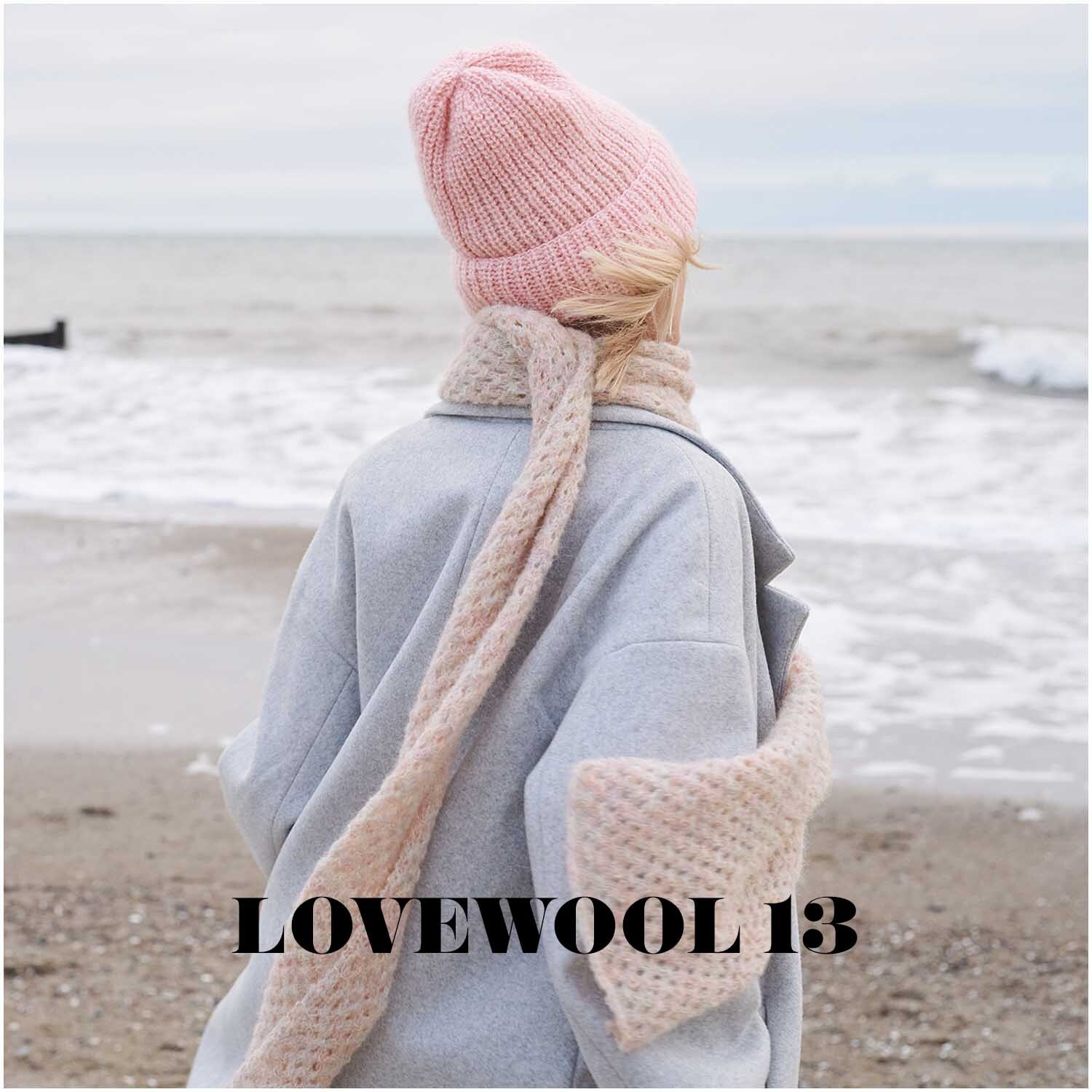 Fashion Skinny Alpaca aran: Person am Strand mit rosa Mütze und Schal aus weicher Wolle, Blick aufs Meer.