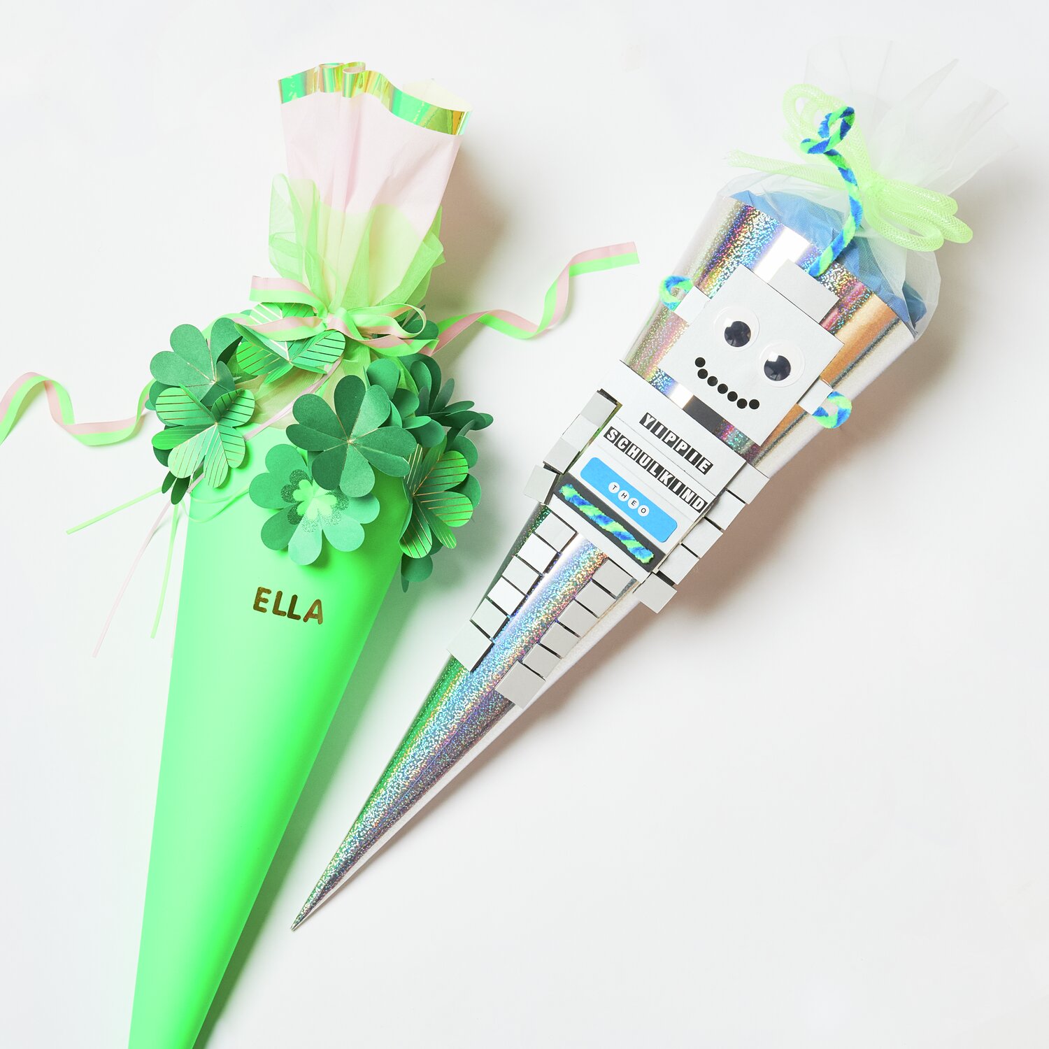 Schultüte Rohling mit Tüllverschluss Neon, 70cm, von Rico Design. Zwei bunte Schultüten, eine mit Kleeblatt-Dekor, die andere mit Roboter-Motiv.