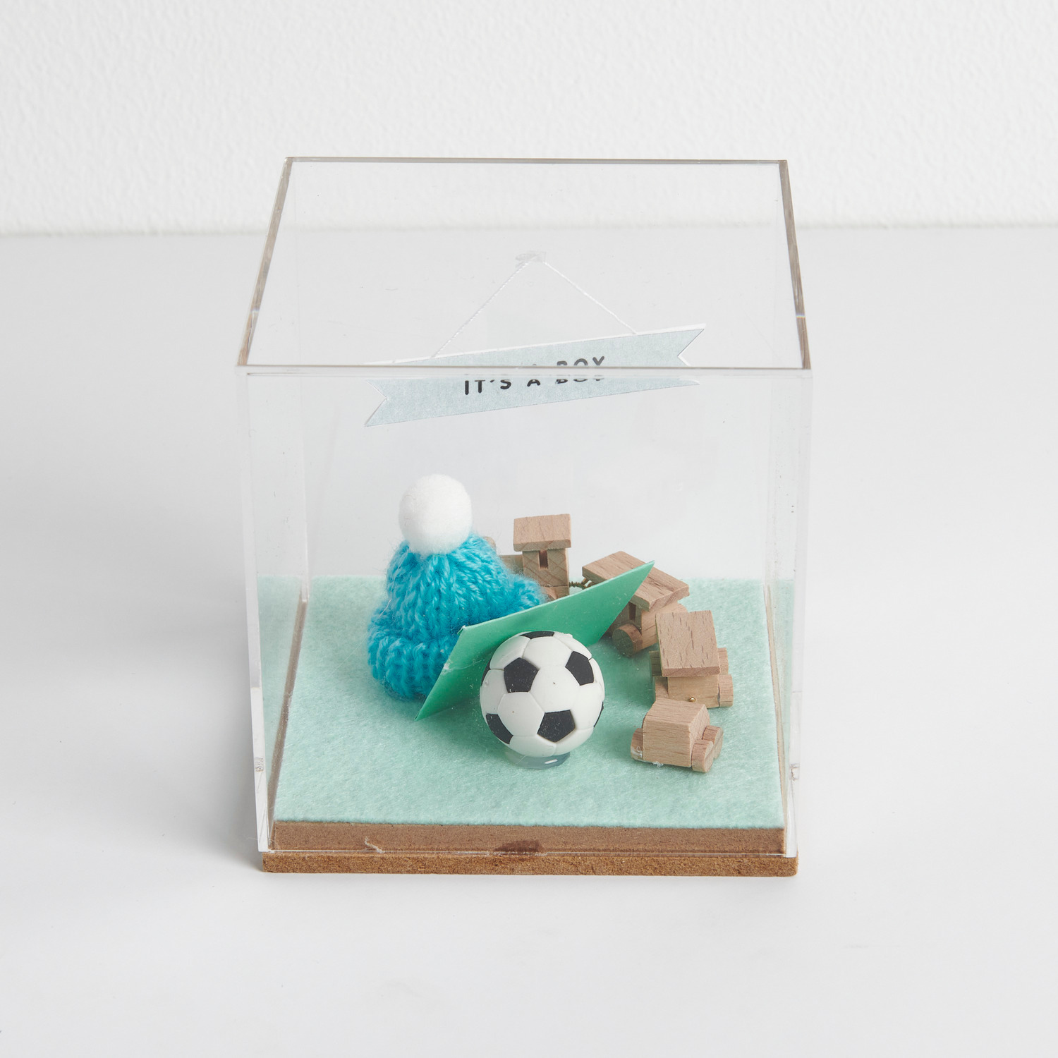 Figurico Dekohaube Würfel mit Miniatur Fußball, blauem Strickmütze und Holzwürfeln in einer transparenten Box.