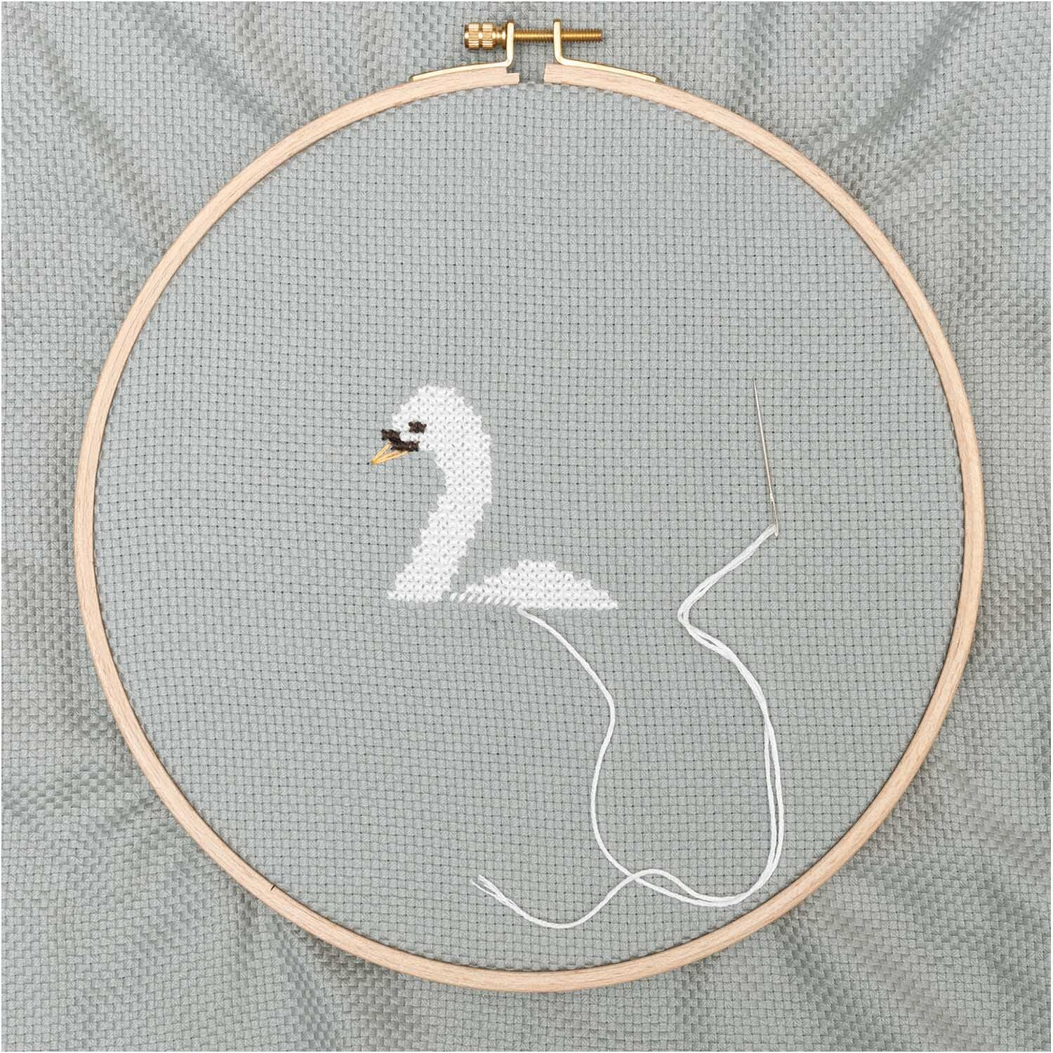 Mönchstoff 4,6 Stiche/cm 50x140cm zeigt einen Stickrahmen mit einem weißen Schwan auf grauem Stoff.